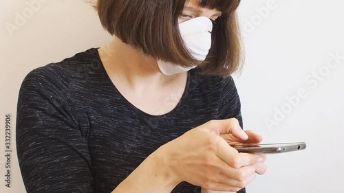 Caucasian young woman wearing face mask during Coronavirus pandemic quarantine using smartphone