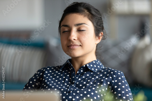 Foto Head shot satisfied peaceful Indian woman relaxing after work done, daydreaming