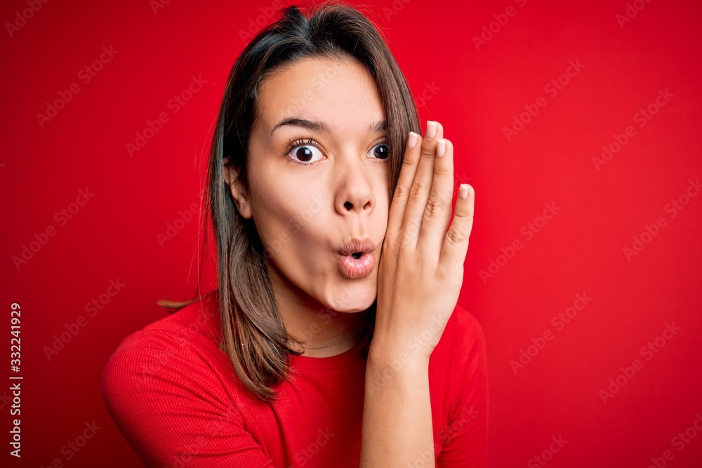Young beautiful brunette girl wearing casual t-shirt over isolated red background hand on mouth telling secret rumor, whispering malicious talk conversation Young beautiful brunette girl wearing casual t-shirt over isolated red background hand on mouth telling secret rumor, whispering malicious talk conversation