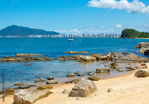 Lancha  no mar, rochas e céu azul na Praia tropical de Ilhota em Itapema, Santa Catarina photo
