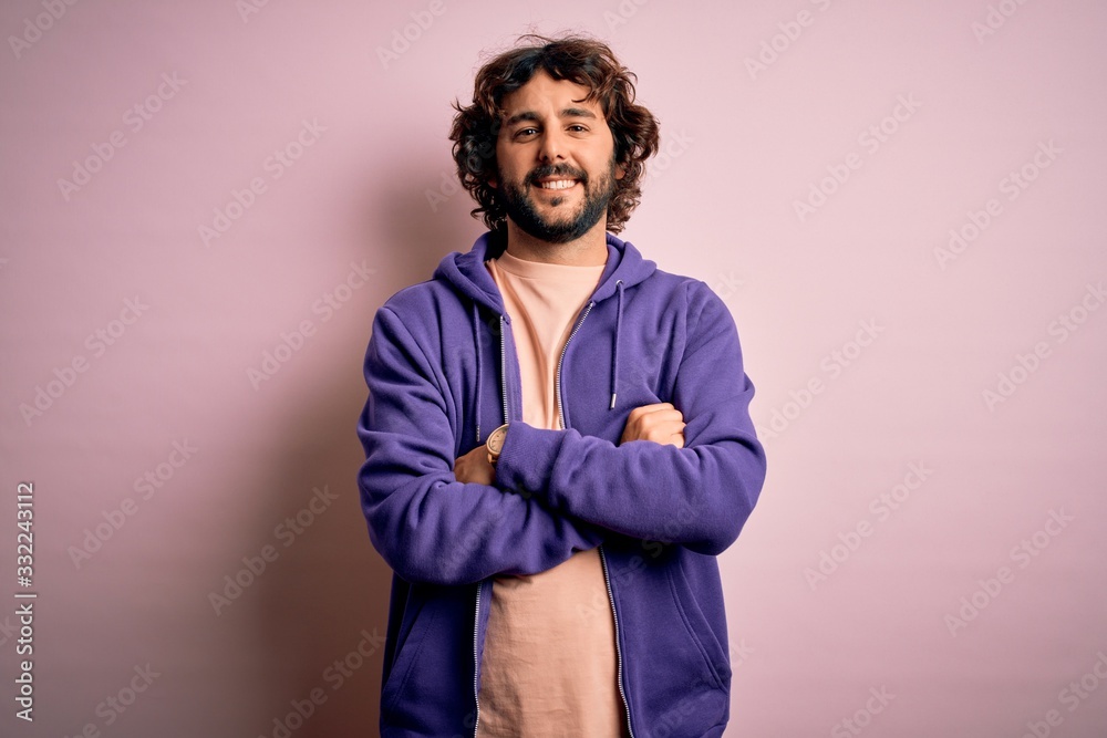 Young handsome sporty man with beard wearing casual sweatshirt over pink background happy face smiling with crossed arms looking at the camera. Positive person. Young handsome sporty man with beard wearing casual sweatshirt over pink background happy face smiling with crossed arms looking at the camera. Positive person.