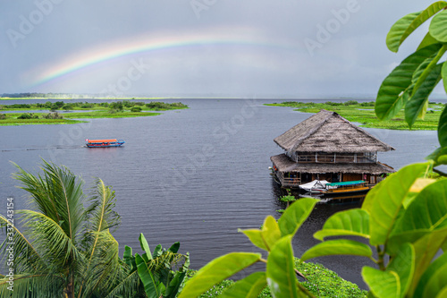 View of the Amazon River tributary in Iquitos, Peru. A rainbow over the river and a beautiful building floating on the water.