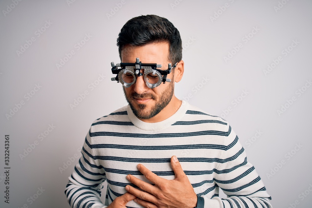 Obraz premium Young handsome man with beard wearing optometry glasses over isolated white background with hand on stomach because indigestion, painful illness feeling unwell. Ache concept.