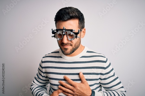 Young handsome man with beard wearing optometry glasses over isolated white background with hand on stomach because indigestion, painful illness feeling unwell. Ache concept.