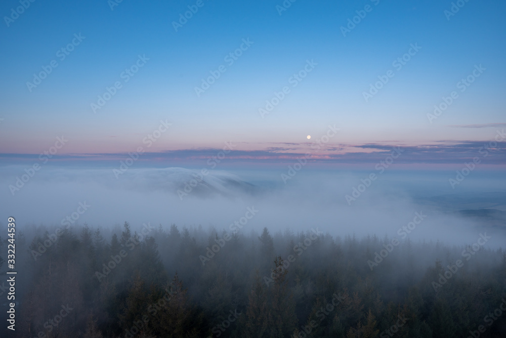 beautiful fog in mountains before sunrise with forest with moon, Czech Beskydy