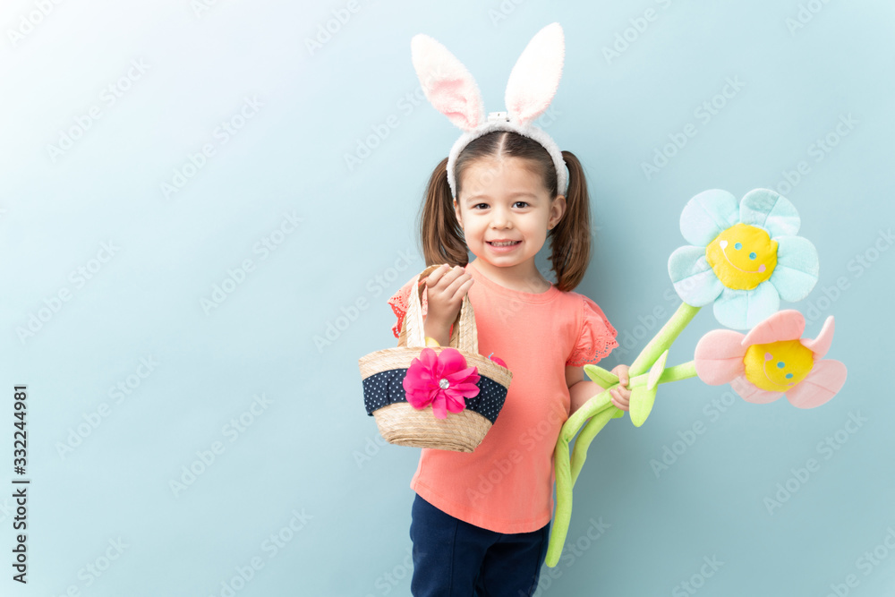 Pretty three year old with bunny ears celebrating Easter against a blue background with copy space Pretty three year old with bunny ears celebrating Easter against a blue background with copy space