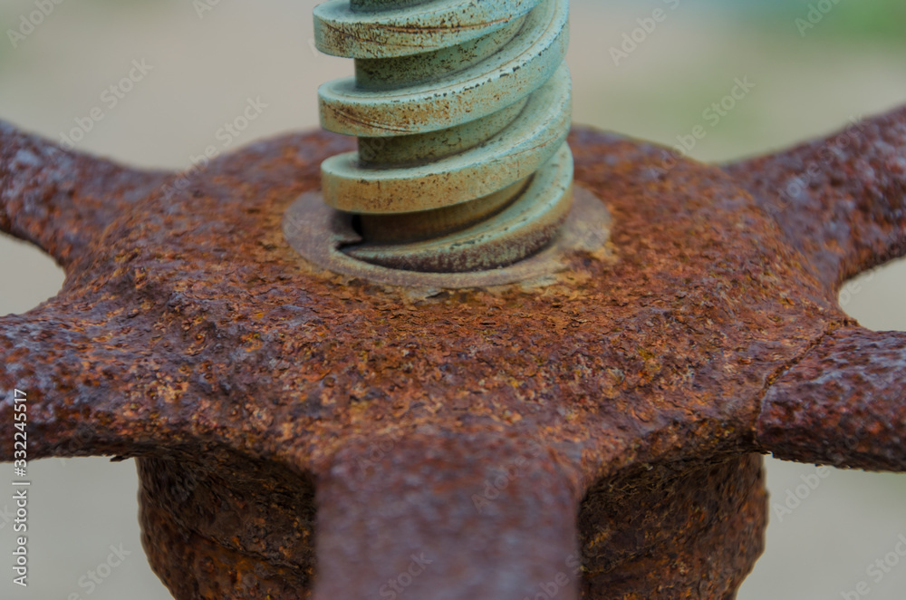 Close up shot of an aged and rusty threaded rod on an old vintage machine with control wheel. Concept of traditional industry. Close up shot of an aged and rusty threaded rod on an old vintage machine with control wheel. Concept of traditional industry.