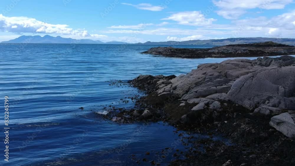 Panning shot by the water on blue ocean island. Aerial video shot by a drone of rocky coastline. Mallaig, Scotland Isle of Skye Panning shot by the water on blue ocean island. Aerial video shot by a drone of rocky coastline. Mallaig, Scotland Isle of Skye