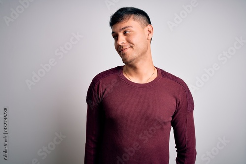 Young handsome hispanic man wearing casual shirt standing over white isolated background smiling looking to the side and staring away thinking.
