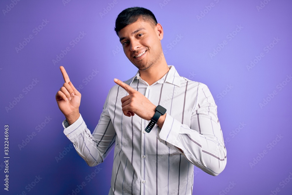 Young handsome hispanic man wearing elegant business shirt standing over purple background smiling and looking at the camera pointing with two hands and fingers to the side. Young handsome hispanic man wearing elegant business shirt standing over purple background smiling and looking at the camera pointing with two hands and fingers to the side.