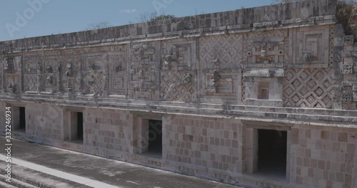 acercamiento de camara hacia muro con alto relieves y esculturas el patio interno de la ciudad maya de uxmal