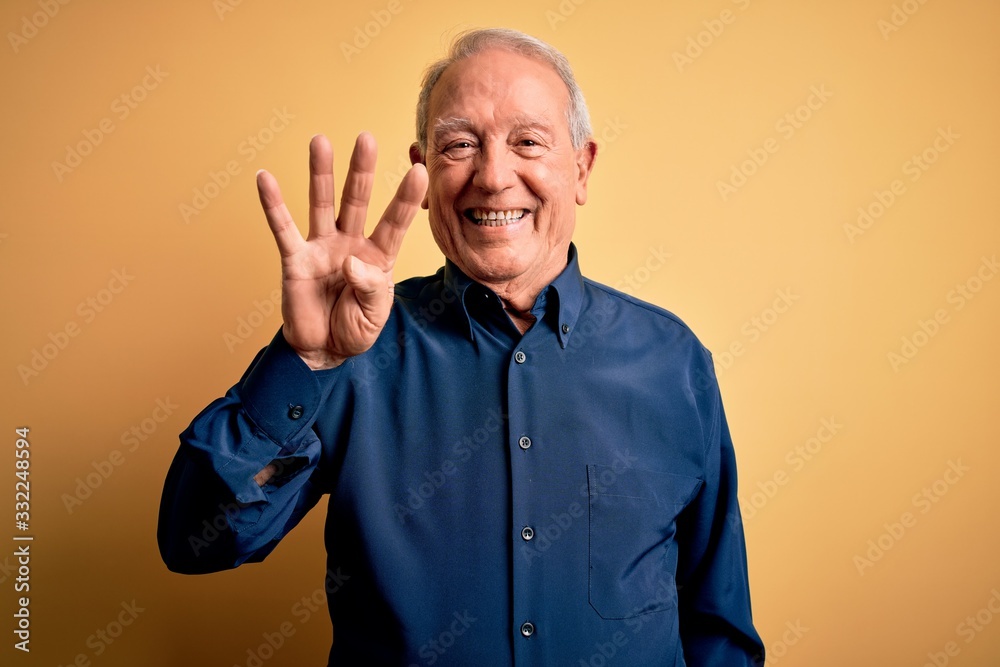 Grey haired senior man wearing casual blue shirt standing over yellow background showing and pointing up with fingers number four while smiling confident and happy. Grey haired senior man wearing casual blue shirt standing over yellow background showing and pointing up with fingers number four while smiling confident and happy.