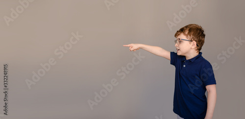 Little boy kid in blue t-shirt and glasses on gray background