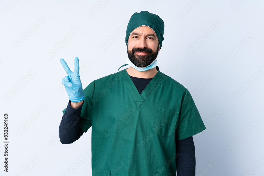 Surgeon man in green uniform over isolated background smiling and showing victory sign Surgeon man in green uniform over isolated background smiling and showing victory sign