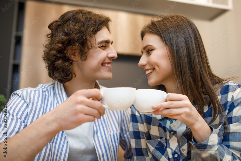 Coffe time at house. Romantic young couple drinking coffee in home kitchen, holding cup Coffe time at house. Romantic young couple drinking coffee in home kitchen, holding cup