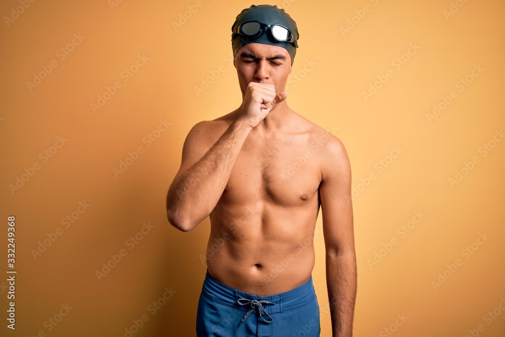 Young handsome man shirtless wearing swimsuit and swim cap over isolated yellow background feeling unwell and coughing as symptom for cold or bronchitis. Health care concept.
