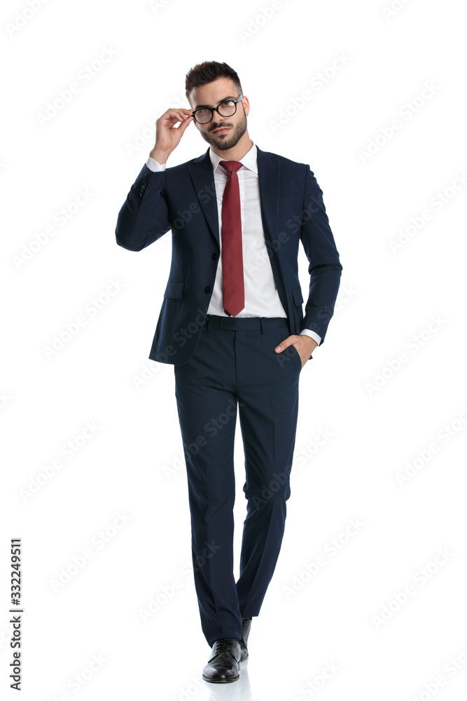 businessman walking with hand in pocket and fixing glasses businessman walking with hand in pocket and fixing glasses