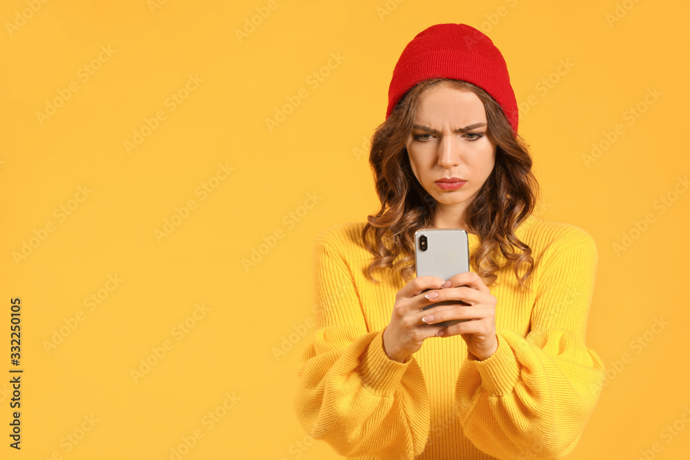 Displeased young woman with mobile phone on color background Displeased young woman with mobile phone on color background