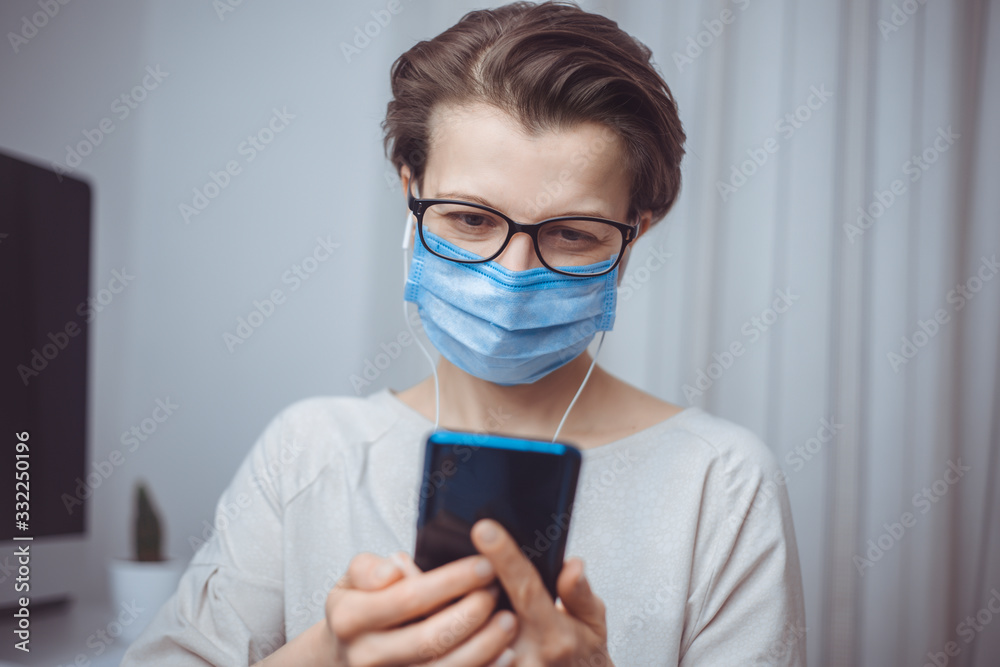 Woman in protective medical mask is talking online on a mobile phone. Video chat on a smartphone.