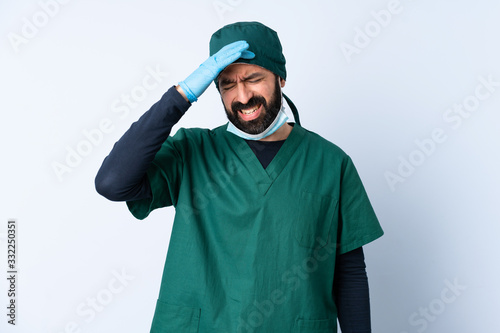 Surgeon man in green uniform over isolated background with headache