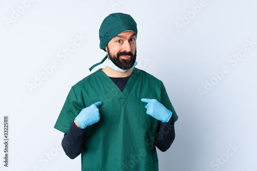 Surgeon man in green uniform over isolated background pointing to oneself