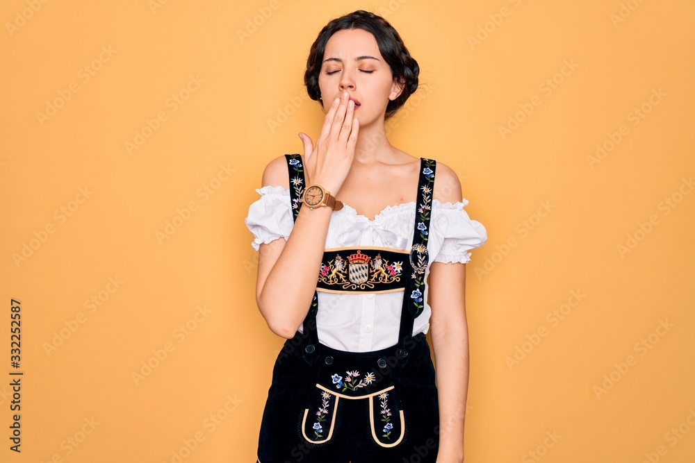 Young beautiful german woman with blue eyes wearing traditional octoberfest dress bored yawning tired covering mouth with hand. Restless and sleepiness. Young beautiful german woman with blue eyes wearing traditional octoberfest dress bored yawning tired covering mouth with hand. Restless and sleepiness.