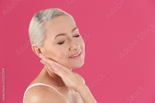 Portrait of beautiful mature woman on pink background. Space for text