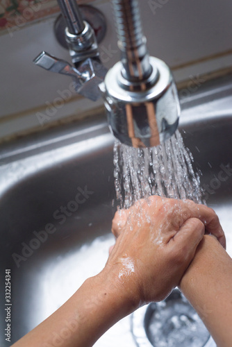 Closeup of handwashing with water at kitchen sink, a prevention measure against Coronavirus photo