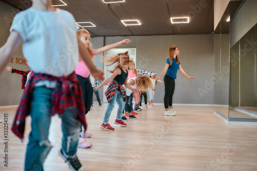 Fototapeta Naklejka Na Ścianę i Meble -  Learning modern dance. Happy boys and girls dancing with female dance teacher in the dance studio
