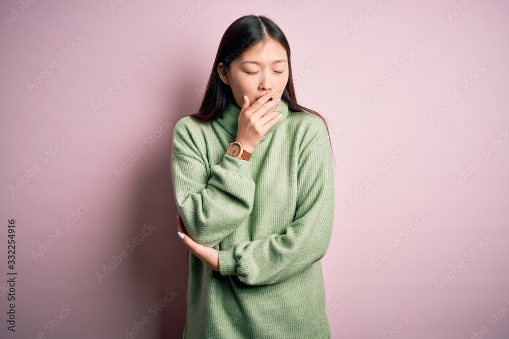 Young beautiful asian woman wearing green winter sweater over pink solated background bored yawning tired covering mouth with hand. Restless and sleepiness. Young beautiful asian woman wearing green winter sweater over pink solated background bored yawning tired covering mouth with hand. Restless and sleepiness.