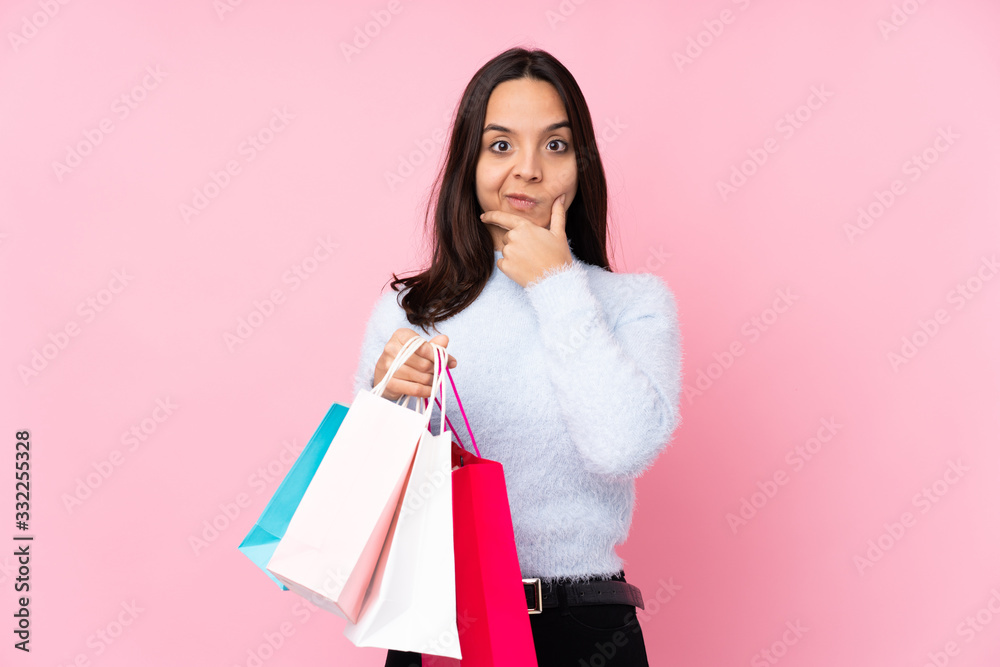 Young woman with shopping bag over isolated pink background thinking