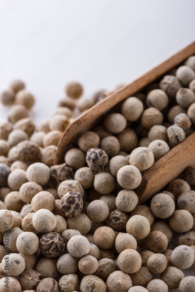 white peppercorns in wooden scoop on white background white peppercorns in wooden scoop on white background