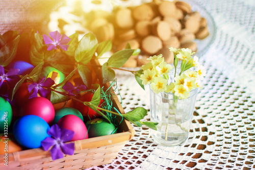 Photos Easter colorful eggs, flowers and greens, white tea-set with eggs inside the cups with butterflies thin porcelain, on a white rounded knitted tablecloth