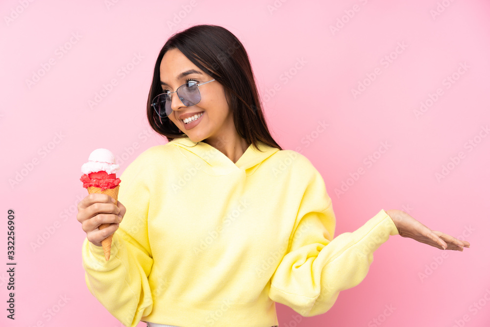 Young brunette girl holding a cornet ice cream over isolated pink background holding copyspace with two hands Young brunette girl holding a cornet ice cream over isolated pink background holding copyspace with two hands
