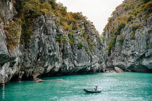 Scenic view of rocks and local fishing boat in the Ha Long Bay of the South China Sea, Vietnam. The Ha Long Bay is a popular tourist destination of Asia.