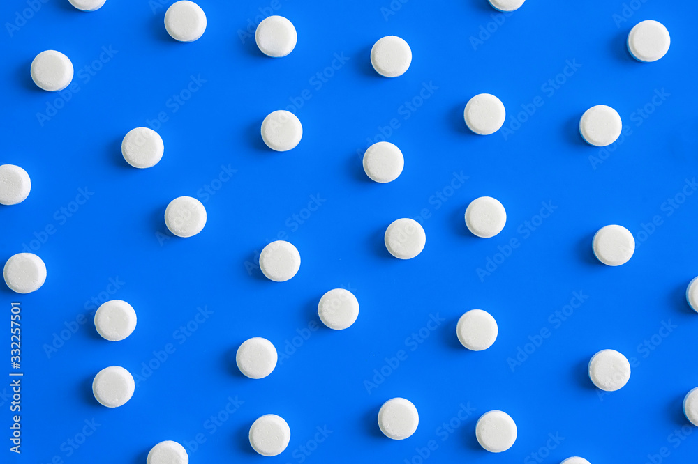 many white pills on a blue background. medicines on the background, texture, pattern