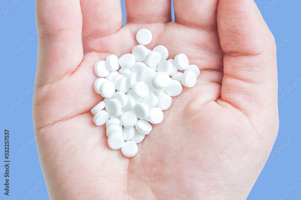 heap of white pills in hand on a white background. handful in hand heap of white pills in hand on a white background. handful in hand