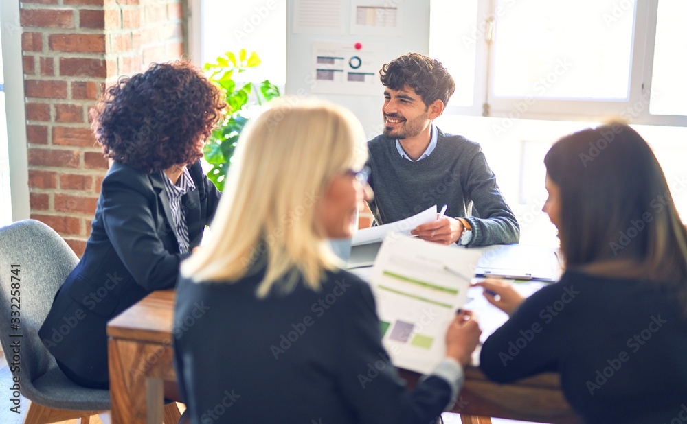 Group of business workers smiling happy and confident. Working together with smile on face using laptop and speaking at the office Group of business workers smiling happy and confident. Working together with smile on face using laptop and speaking at the office