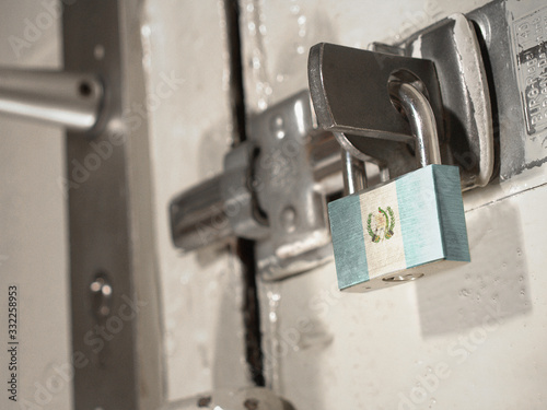 A bolted door secured by a padlock with the national flag of Guatemala on it.(series)