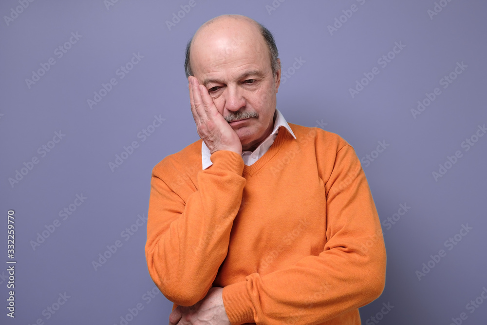 Sad mature hispanic man in orange sweater feeling stressed and alone. Sad mature hispanic man in orange sweater feeling stressed and alone.