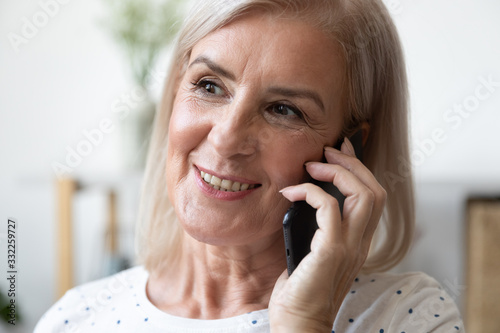Fotografie, Obraz Close up head shot portrait happy elder blonde woman talking on mobile phone with grown up adult children or friends