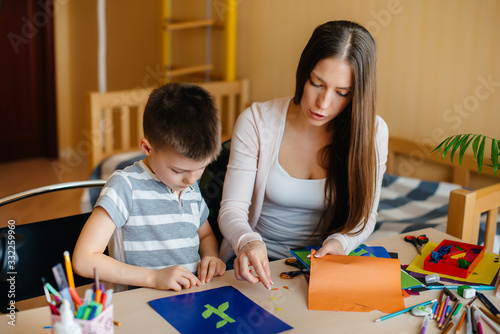 A young mother is doing homework with her son at home. Parents and training