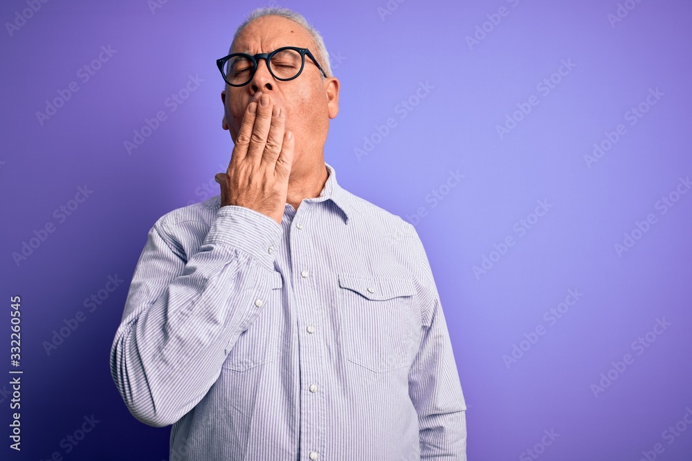 Middle age handsome hoary man wearing striped shirt and glasses over purple background bored yawning tired covering mouth with hand. Restless and sleepiness.