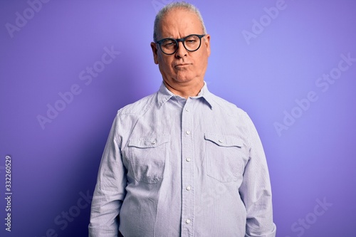 Middle age handsome hoary man wearing striped shirt and glasses over purple background depressed and worry for distress, crying angry and afraid. Sad expression.