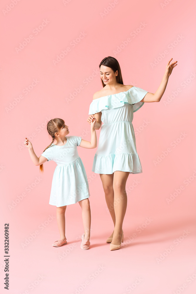 Happy mother and her little daughter dancing against color background Happy mother and her little daughter dancing against color background