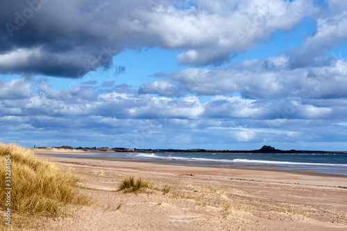 Deserted Beach with huge cloudy  blue sky and sand dunes in the foreground  Bamburgh  Northumberland  Uk