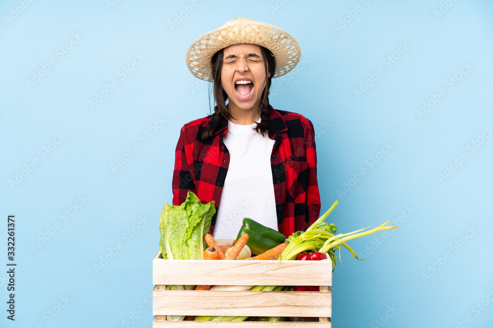 Young farmer Woman holding fresh vegetables in a wooden basket shouting to the front with mouth wide open