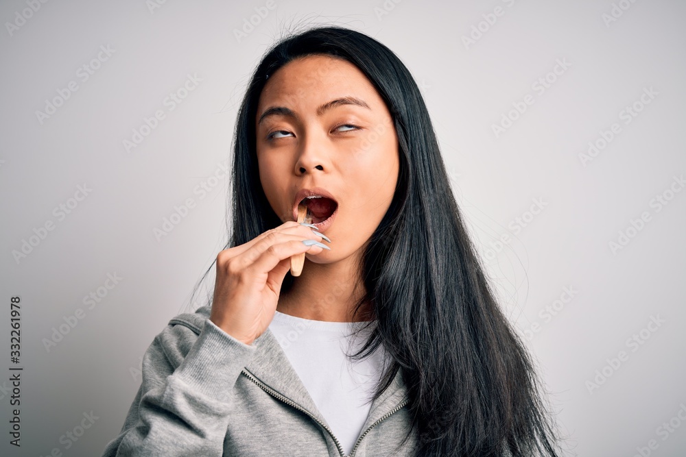 Young beautiful woman standing whasing tooth using toothbrush over isolated white background Young beautiful woman standing whasing tooth using toothbrush over isolated white background