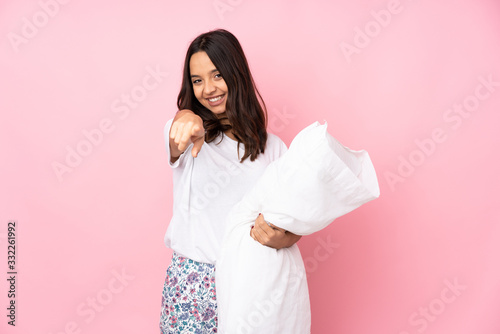 Young woman in pajamas isolated on pink background points finger at you with a confident expression
