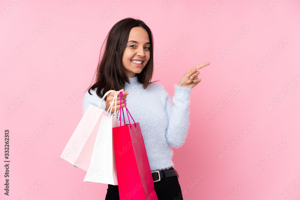 Young woman with shopping bag over isolated pink background pointing finger to the side Young woman with shopping bag over isolated pink background pointing finger to the side